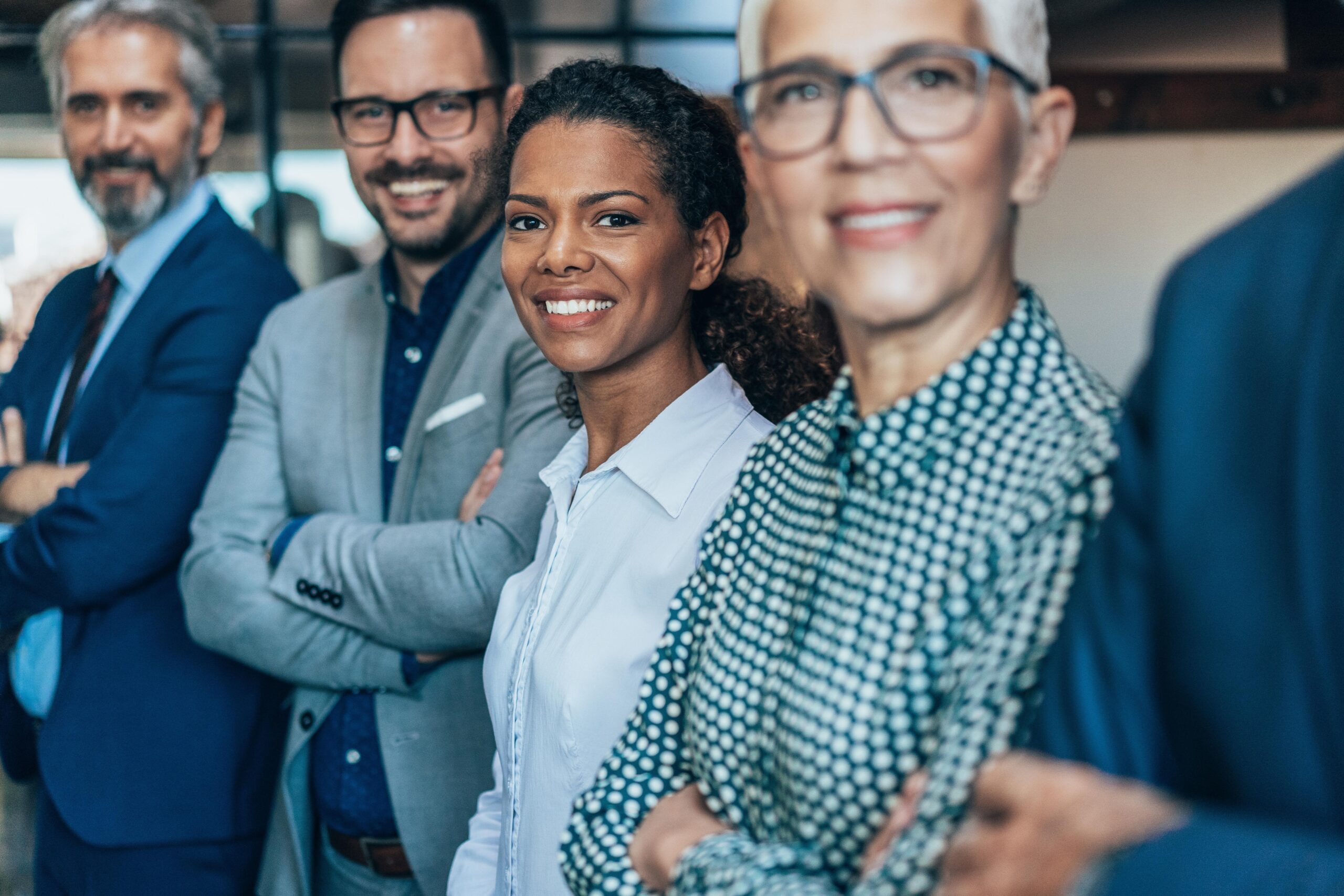 smiling-group-diverse-businesspeople-working-together-around-meeting-table-office-complex-lobby Smiling group of diverse businesspeople working together around a meeting table in an office complex lobby